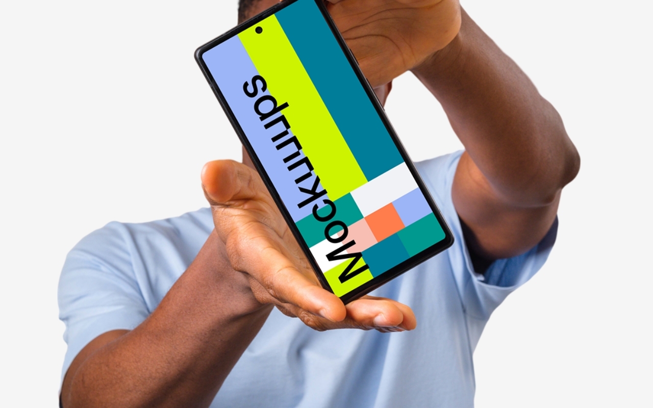 Young African-American man holding Google Pixel mockup in light blue shirt on white background, device mockup template