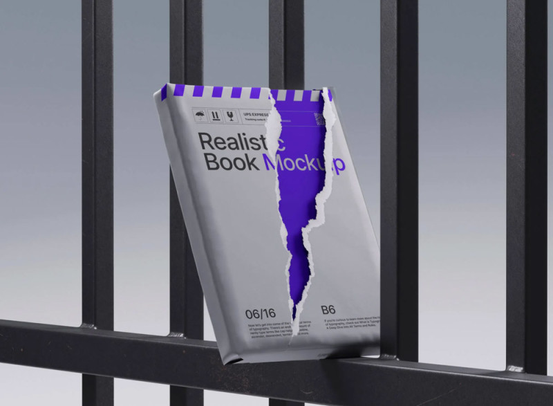 A book placed against a black metal railing shows a cover design with a torn effect, exposing a purple layer underneath